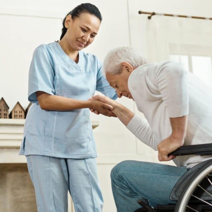 Happy caregiver assisting client as he stands from wheelchair