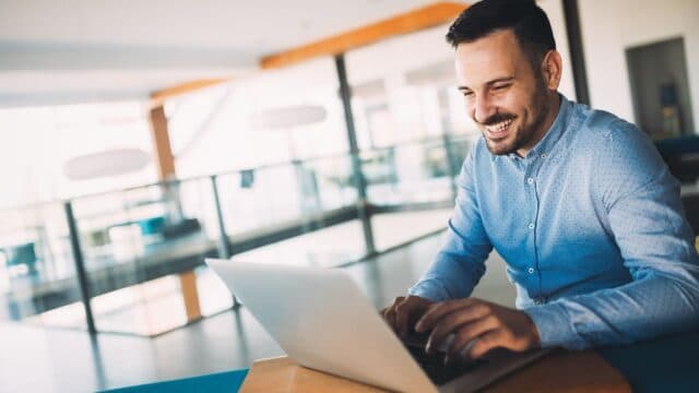 Smiling man on laptop in office setting