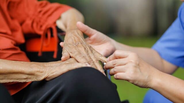 Healthcare worker holding hand of elderly client