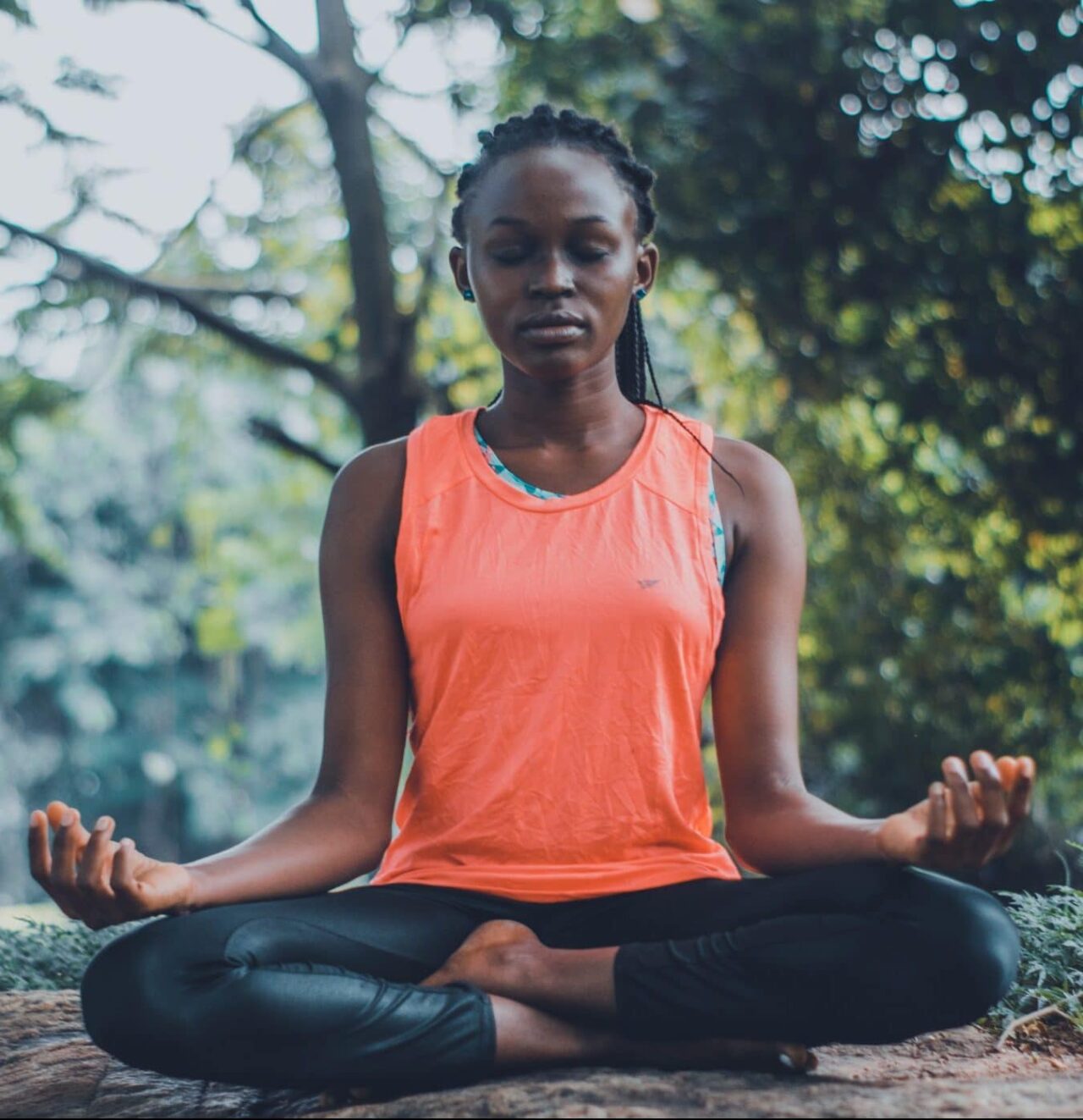 Woman sitting down and meditating in the outdoors.