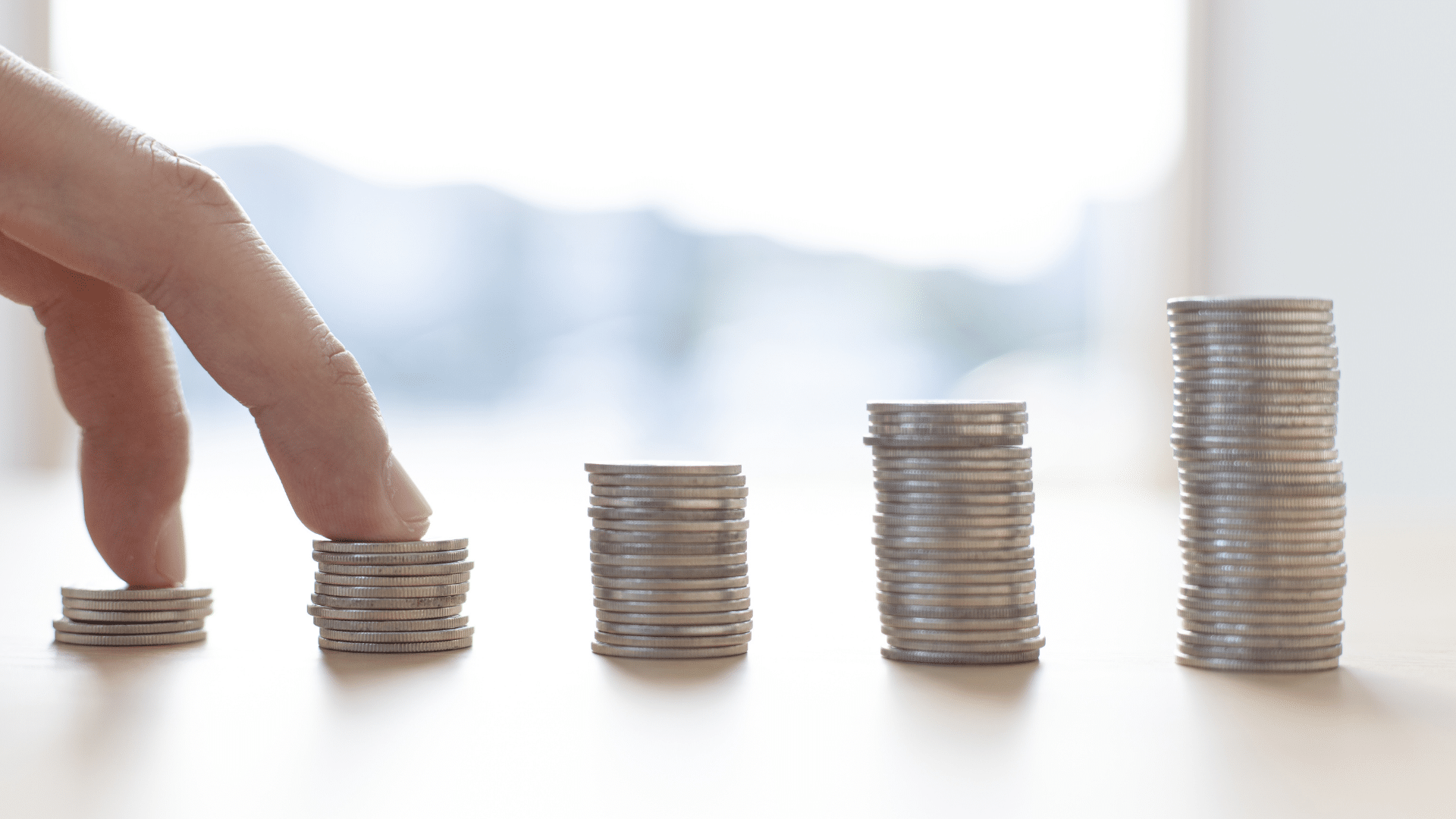 fingers stacking coins on a table