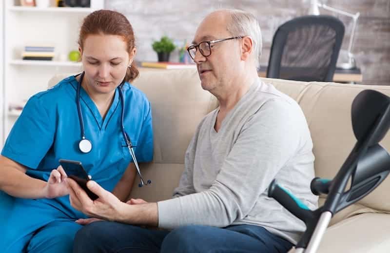 a caregiver showing an elderly man something on his phone