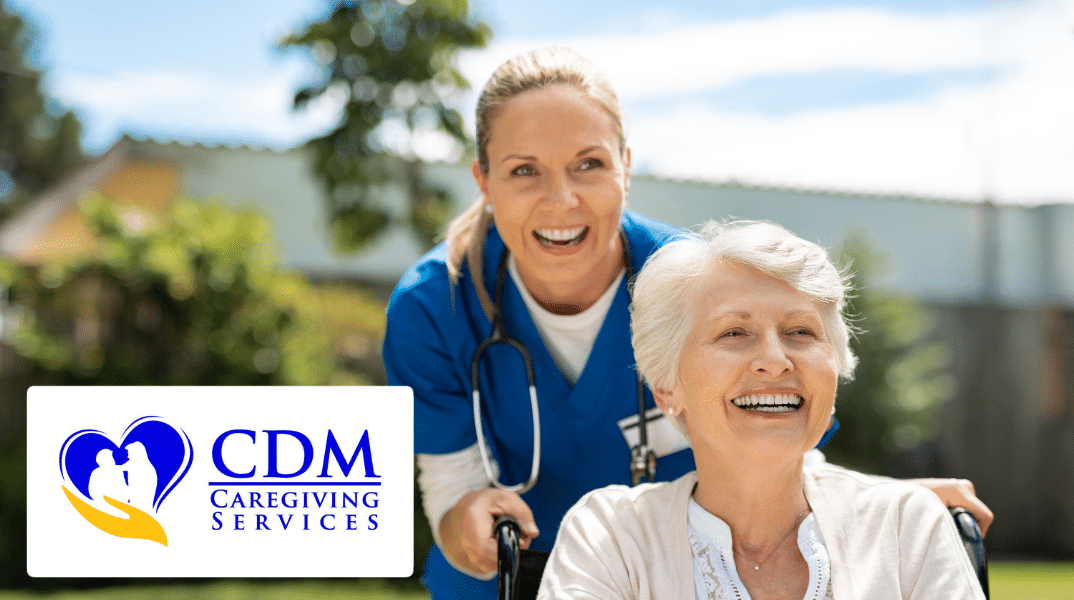 An eldery person is pushed in a wheelchair by a caregiver. CDM Caregiving Services logo is in the bottom left corner.