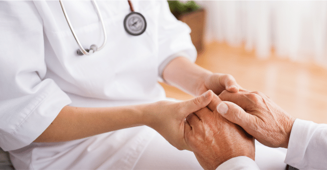 nurse and elderly patient holding hands