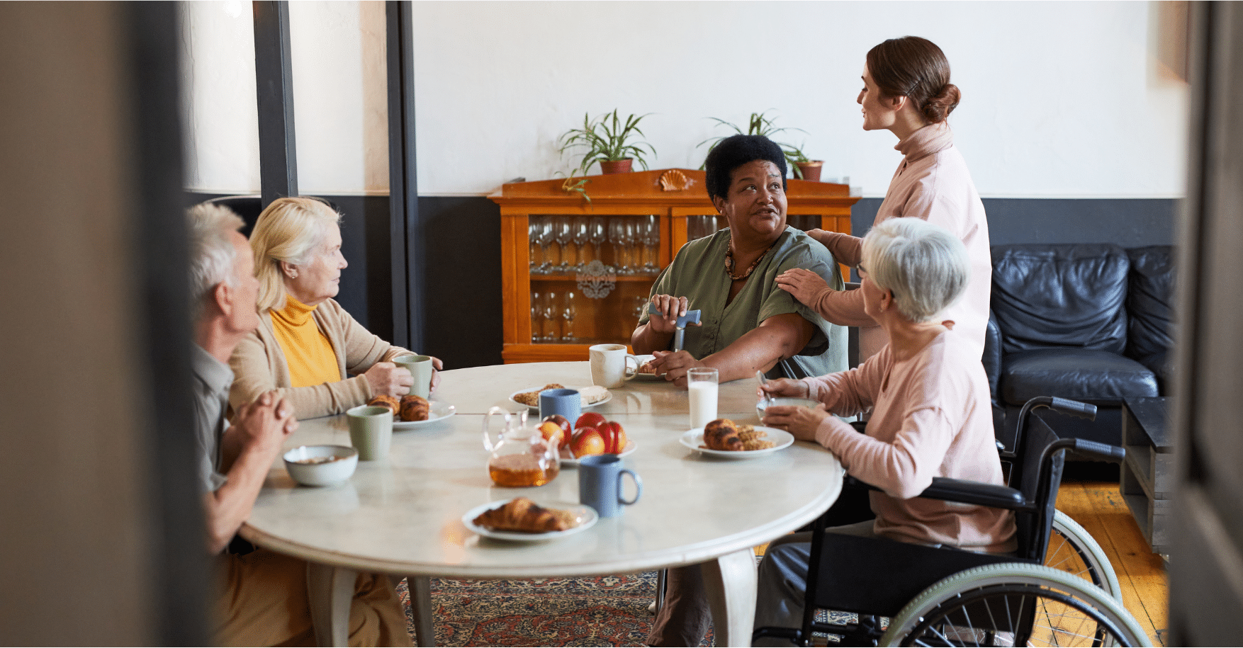 elderly people sitting at table with caregiver