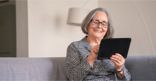 elderly woman smiling holding tablet