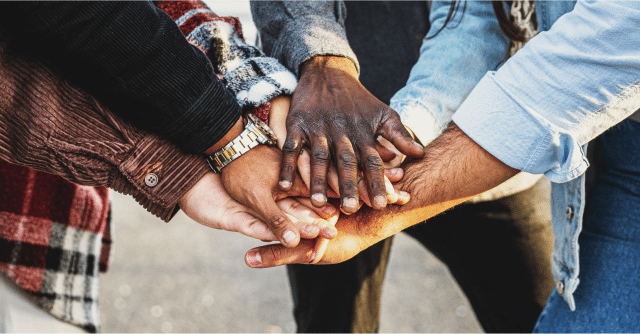 racially diverse hands together in support as a team